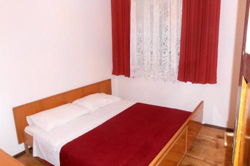 a bedroom with a bed and a window with red curtains at Apartments with a parking space Vrisnik, Hvar - 4051 in Jelsa