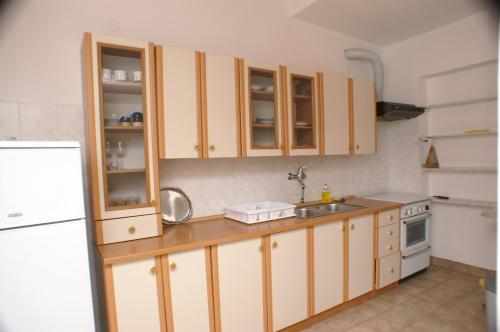 a kitchen with wooden cabinets and a sink and a refrigerator at Apartments by the sea Sepurine, Prvic - 4238 in Prvić Šepurine