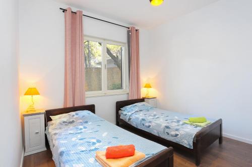 two twin beds in a room with a window at Apartments by the sea Balica Rat, Omis - 1065 in Omiš