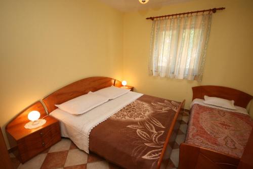 a bedroom with two beds and a window with two lamps at Apartments by the sea Kustici, Pag - 4081 in Zubovići