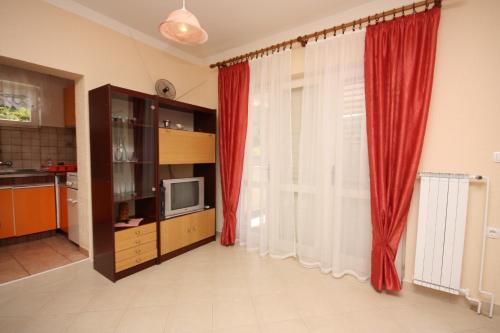 a living room with red curtains and a television at Apartments and rooms by the sea Supetarska Draga - Donja, Rab - 2001 in Rab