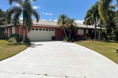 a driveway in front of a house with palm trees at Heated Pool Paradise, Gulf Access, Pet Friendly in Port Charlotte