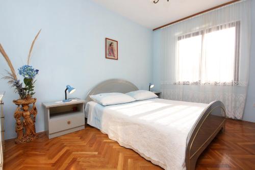 a white bedroom with a bed and a window at Apartments by the sea Slatine, Ciovo - 2039 in Slatine