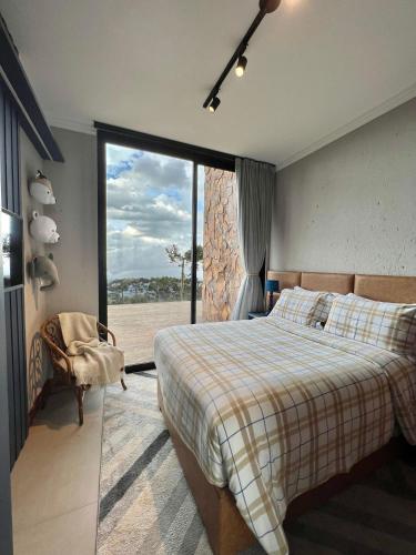 a bedroom with a bed and a large window at Sion Vivendas da Serra in Urubici