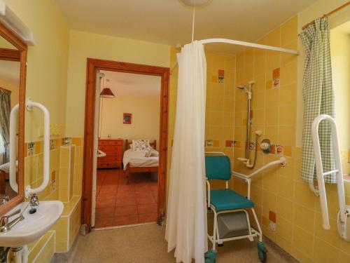 y baño con lavamanos, ducha y silla. en Mimosa Cottage, en Swyre