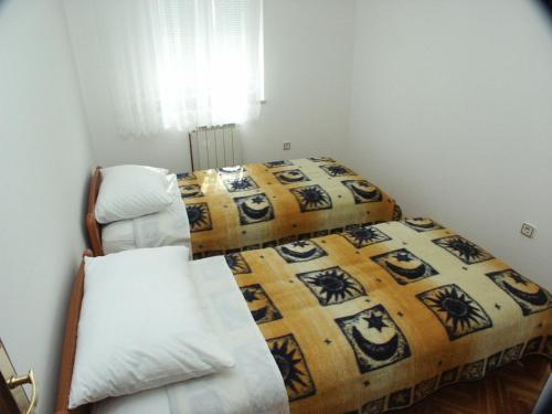 two beds in a small room with a bed and a chair at Apartments by the sea Seget Donji, Trogir - 2041 in Trogir