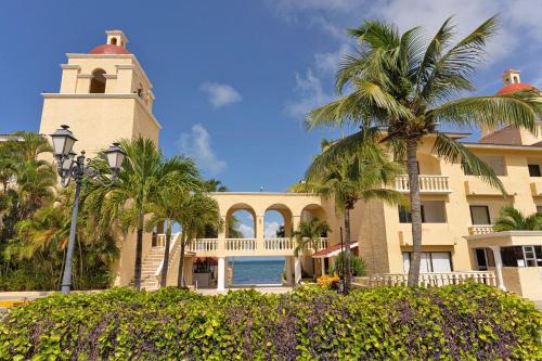 a building with a clock tower and palm trees at All Ritmo Cancun Resort & Water Park in Cancún