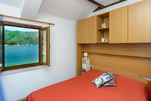 a bedroom with a large window and a bed with red sheets at Apartments and rooms by the sea Zaton Veliki, Dubrovnik - 2110 in Zaton