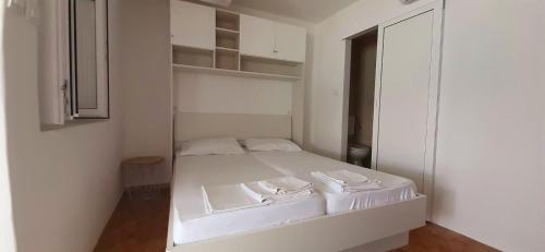 a small white bedroom with a bed and a closet at Double Room Sladjenovici 2161d in Slano