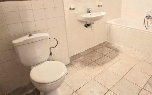 a white bathroom with a toilet and a sink at Ruim nostalgisch gelijkvloers appartement op wandelafstand van de zee in Blankenberge