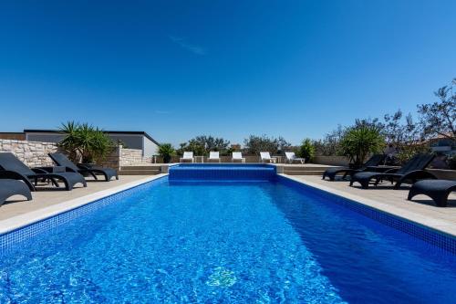 a swimming pool with chaise lounge chairs next to it at Family friendly apartments with a swimming pool Valbandon, Fazana - 2201 in Štinjan