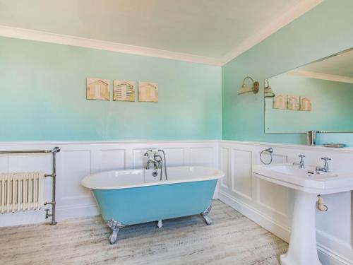 y baño con bañera azul y lavamanos. en Bryn Rhosyn, en Pwllheli