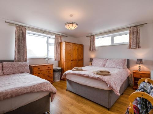 a bedroom with two beds and two windows at Halcyon in Tintagel