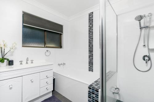 een witte badkamer met een douche en een wastafel bij Iona in Iluka