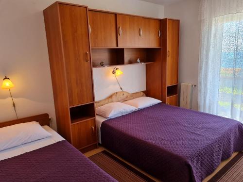 een slaapkamer met 2 bedden, kasten en een raam bij Apartments with a parking space Lun, Pag - 4062 in Lun
