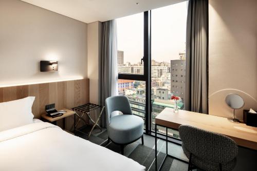 una camera d'albergo con letto, scrivania e finestra di G3 Hotel Chungmuro a Seul