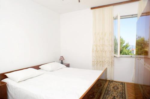 biała sypialnia z łóżkiem i oknem w obiekcie Family friendly seaside apartments Vlasici, Pag - 4131 w mieście Vlašići
