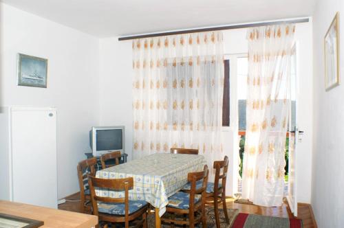 jadalnia ze stołem i krzesłami oraz oknem w obiekcie Family friendly seaside apartments Vlasici, Pag - 4131 w mieście Vlašići