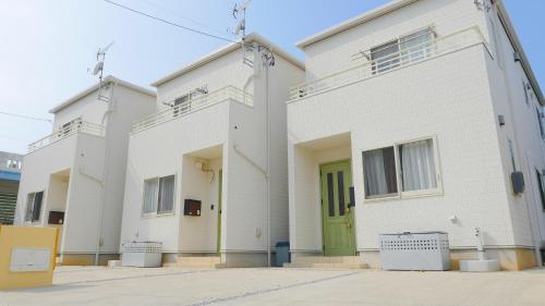 a white building with a green door at グランディオーソ沖縄ヴィラ恩納5 in Onna