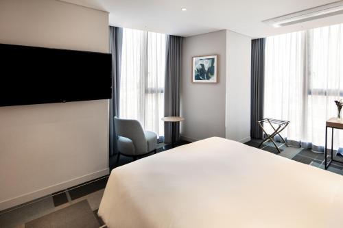 ソウルにあるG3 Hotel Chungmuroのベッド1台、薄型テレビが備わるホテルルームです。