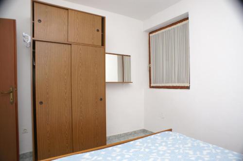 a bedroom with a wooden cabinet and a bed at Apartment Novalja 4114a in Novalja