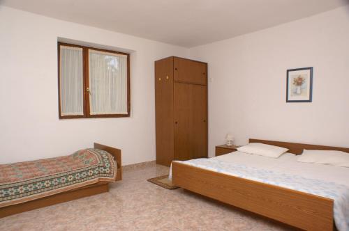 een slaapkamer met 2 bedden, een kast en een raam bij Apartment Novalja 4114d in Novalja