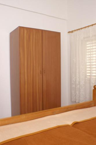 a bedroom with a wooden cabinet next to a window at Apartment Grebastica 4207b in Bašelovići