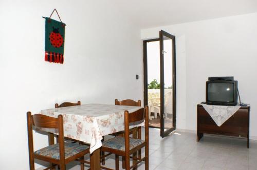ein Esszimmer mit einem Tisch und einem TV in der Unterkunft Apartments with a parking space Potocnica, Pag - 4096 in Stara Novalja