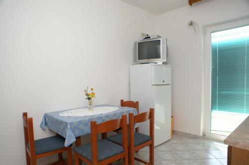 una pequeña cocina con mesa, sillas y nevera. en Apartment Zubovici 4130e, en Zubovići