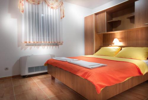una camera da letto con letto con lenzuola arancioni e cuscini gialli di Apartments with a swimming pool Caska, Pag - 4109 a Novalja (Novaglia)