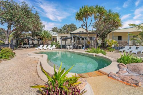 una piscina in un cortile con sedie e alberi di Fraser Island Beach Houses a Fraser Island