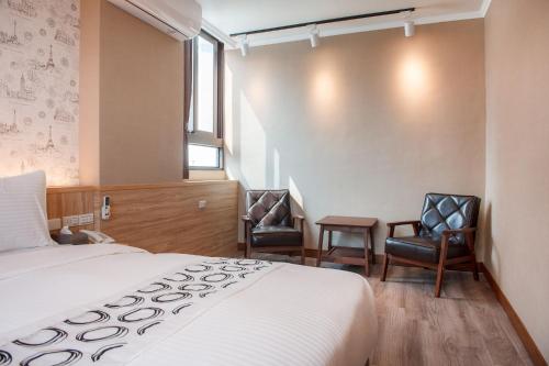 een hotelkamer met een bed en twee stoelen bij Shan Shui Hostel in Hualien