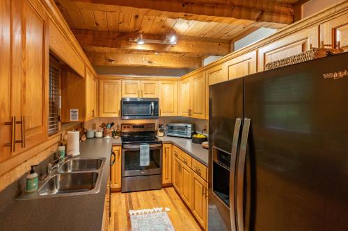 a kitchen with wooden cabinets and a stainless steel refrigerator at Creekside Cabin - Seven Devils,NC - Pet-Friendly, Close to Hiking & Fishing, and Family Games! in Seven Devils
