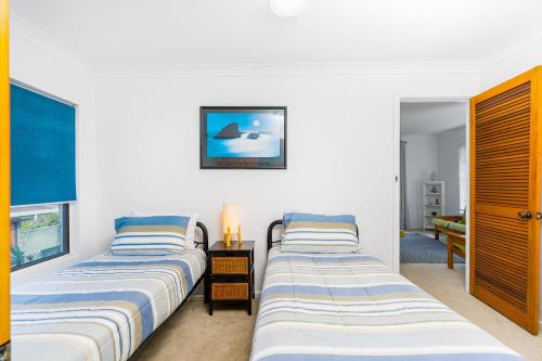 two beds in a room with white walls at Pelicans Eleven Iluka Villa 11 in Iluka