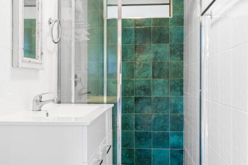 a bathroom with a sink and a shower with green tiles at Pelicans Eleven Iluka Villa 11 in Iluka