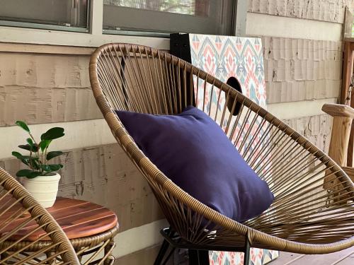a wicker chair with a blue pillow on a porch at Creekside Cabin - Seven Devils,NC - Pet-Friendly, Close to Hiking & Fishing, and Family Games! in Seven Devils