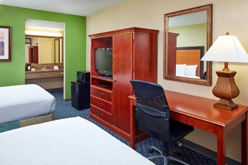 a hotel room with a desk and a bed and a mirror at La Quinta by Wyndham Thousand Oaks-Newbury Park in Thousand Oaks
