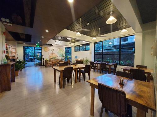 ein Restaurant mit Holztischen, Stühlen und Fenstern in der Unterkunft Acacia Garden Inn in Coron