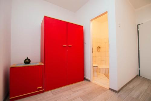 Cette chambre comprend une armoire rouge et une salle de bains. dans l'établissement Apartment Arbanija 1122b, à Trogir