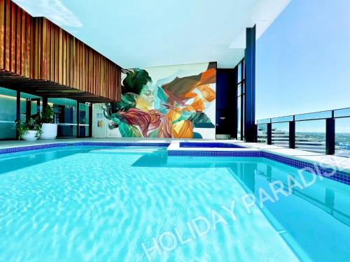 a swimming pool with a mural on the side of a building at Luxury S Casino Residences Broadbeach - Holiday Paradise in Gold Coast