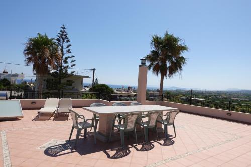 a table and chairs on a patio with palm trees at Villa Harriet Maria with pool and ocean view Kolimbari, Chania in Kolymvari