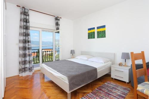 a white bedroom with a bed and a balcony at Apartments and rooms by the sea Arbanija, Ciovo - 1125 in Trogir