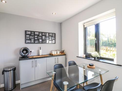 a dining room with a glass table and chairs at The Coach House, Bank Top Farm in Ashbourne
