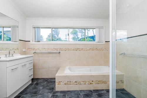 a bathroom with a tub and a sink and a shower at Bayhaven in Iluka