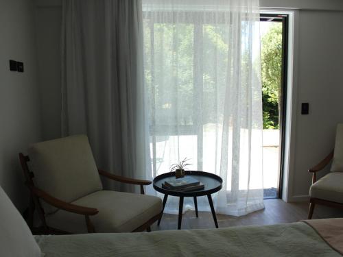 1 dormitorio con silla, mesa y ventana en māra, en Mapua