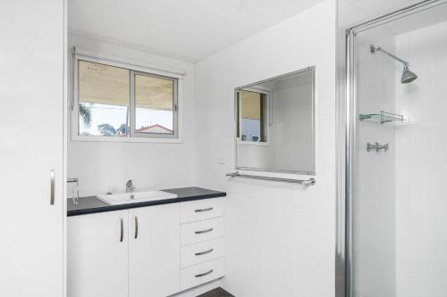 a white bathroom with a sink and a shower at Omaroo Prestige Waterfront in Iluka