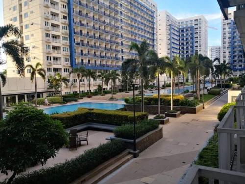 a resort with a pool and palm trees and buildings at Bliss by John at Sea Residences in Manila