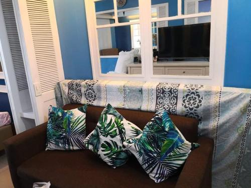 a couch with pillows on it in a living room at Bliss by John at Sea Residences in Manila
