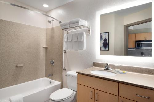 La salle de bains est pourvue de toilettes, d'un lavabo et d'un miroir. dans l'établissement Candlewood Suites Watertown Fort Drum, an IHG Hotel, à Evans Mills