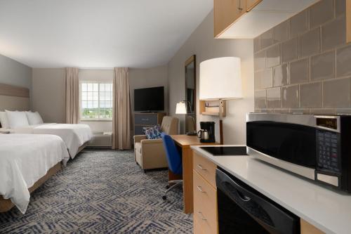 a hotel room with two beds and a television at Candlewood Suites Watertown Fort Drum, an IHG Hotel in Evans Mills